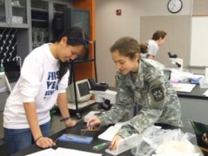 Two female service women examine an object on a table